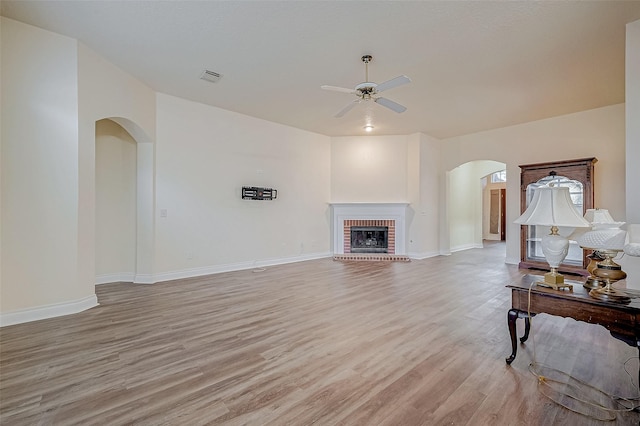 living room featuring a fireplace, light hardwood / wood-style flooring, and ceiling fan