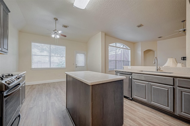 kitchen with stainless steel appliances, a kitchen island, sink, and light wood-type flooring