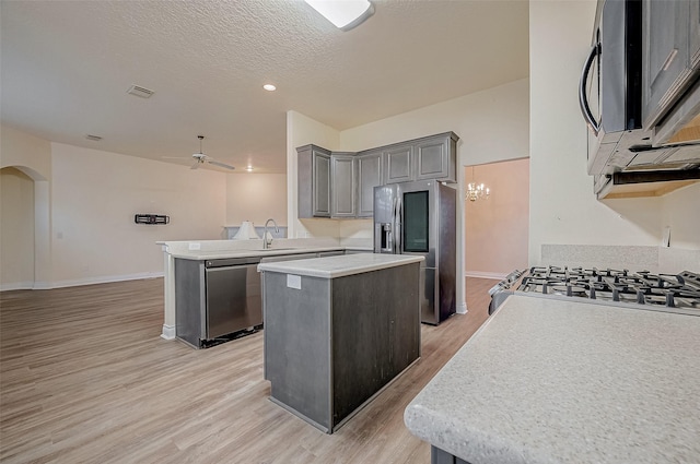 kitchen with sink, appliances with stainless steel finishes, gray cabinetry, a center island, and kitchen peninsula