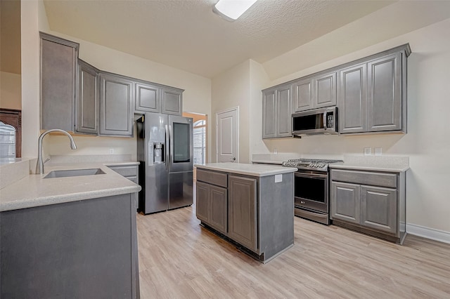 kitchen with stainless steel appliances, a center island, sink, and gray cabinetry