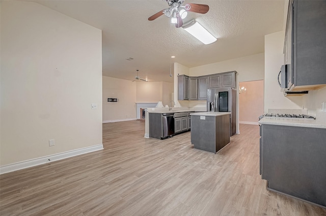 kitchen with ceiling fan, appliances with stainless steel finishes, gray cabinetry, a textured ceiling, and a kitchen island