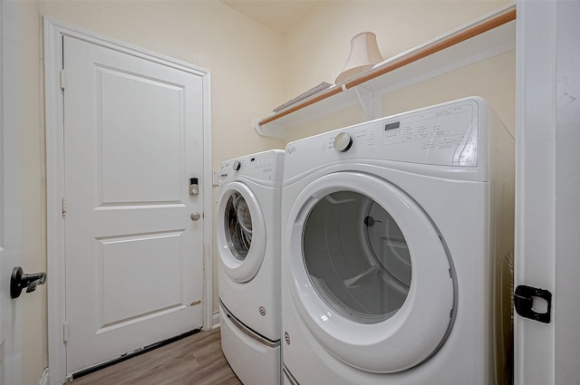 clothes washing area with washing machine and dryer and light hardwood / wood-style flooring