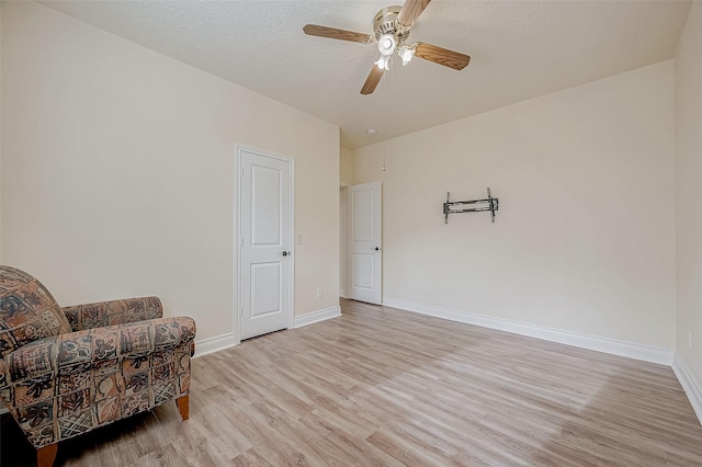 living area with ceiling fan, a textured ceiling, and light wood-type flooring