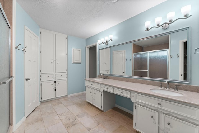 bathroom with vanity, a textured ceiling, and walk in shower