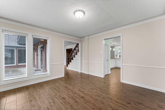 spare room featuring crown molding, dark wood-type flooring, and a textured ceiling