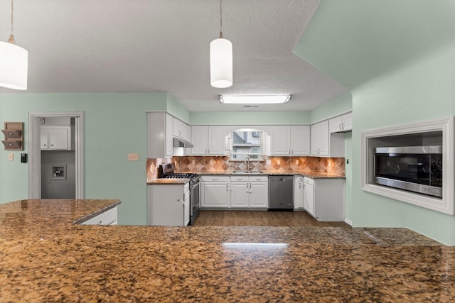 kitchen featuring tasteful backsplash, white cabinetry, sink, hanging light fixtures, and stainless steel appliances