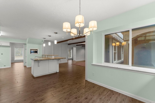 kitchen featuring an inviting chandelier, hanging light fixtures, dark hardwood / wood-style floors, and a kitchen bar