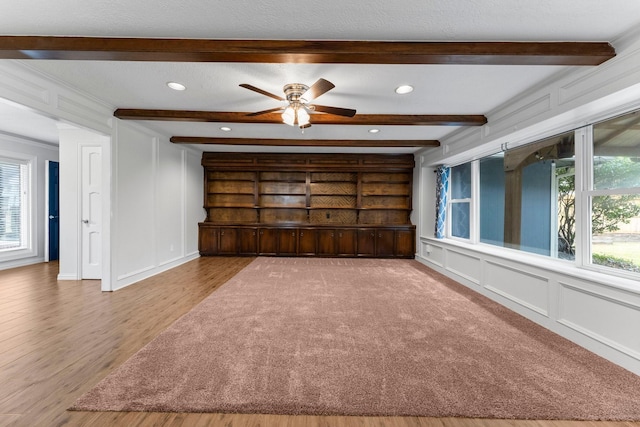 spare room with crown molding, ceiling fan, hardwood / wood-style flooring, and beamed ceiling