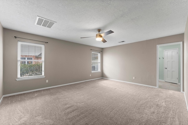 carpeted spare room featuring ceiling fan and a textured ceiling