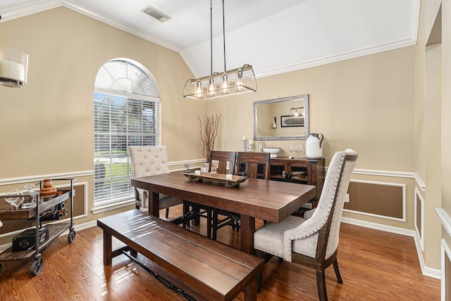 dining room with hardwood / wood-style flooring, ornamental molding, and lofted ceiling