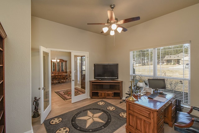 home office with ceiling fan with notable chandelier, french doors, and light wood-type flooring