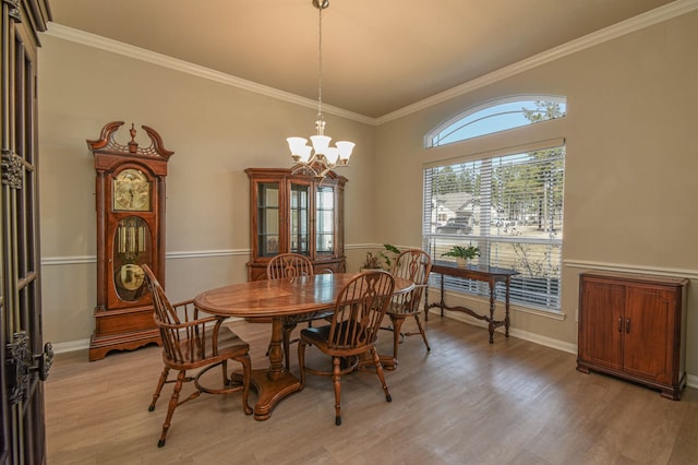 dining area with ornamental molding, light wood-type flooring, and a notable chandelier