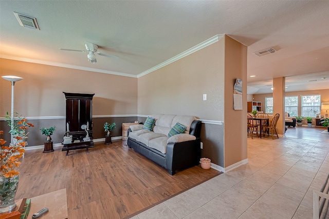 living room with ceiling fan, light tile patterned floors, and crown molding