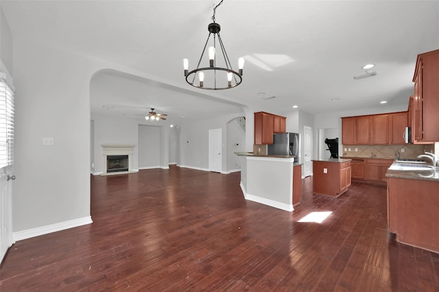 kitchen with appliances with stainless steel finishes, tasteful backsplash, dark hardwood / wood-style flooring, hanging light fixtures, and a center island