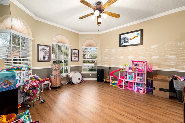 recreation room featuring hardwood / wood-style flooring, crown molding, and ceiling fan