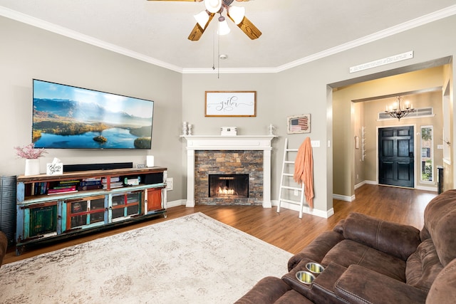 living room featuring ceiling fan with notable chandelier, hardwood / wood-style floors, ornamental molding, and a fireplace