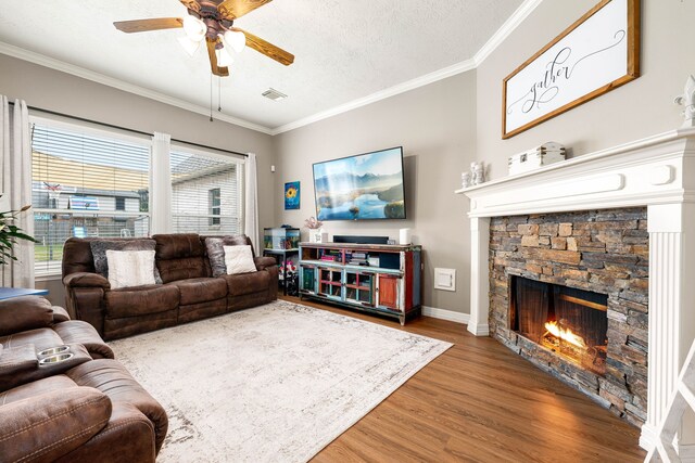 living room with a textured ceiling, ornamental molding, hardwood / wood-style floors, and a fireplace