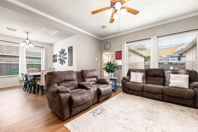 living room with hardwood / wood-style flooring, a textured ceiling, ornamental molding, and ceiling fan with notable chandelier