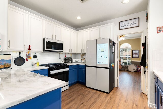 kitchen with white cabinets, black gas stove, and stainless steel fridge