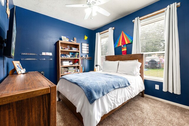 carpeted bedroom with ceiling fan and a textured ceiling