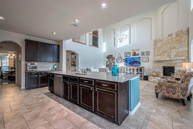 kitchen with sink, dark brown cabinets, stainless steel dishwasher, and a center island with sink