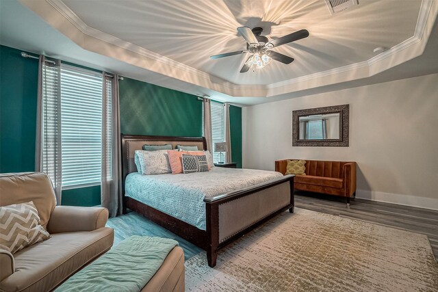 bedroom featuring a raised ceiling, hardwood / wood-style floors, ceiling fan, and multiple windows