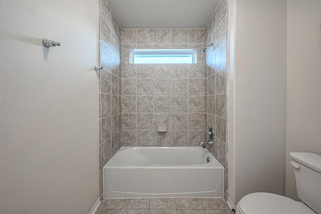 bathroom with tile patterned flooring, tiled shower / bath combo, and toilet