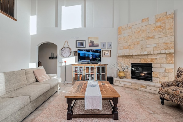 living room with a high ceiling and a stone fireplace