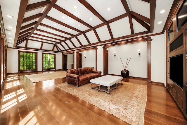 living room featuring hardwood / wood-style flooring, ornate columns, and vaulted ceiling with beams