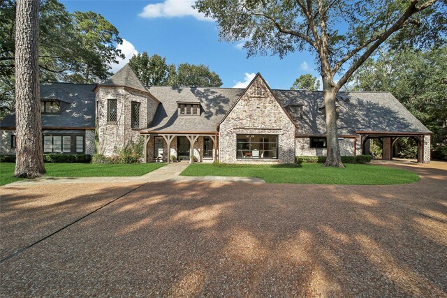 tudor home with a front yard and a carport