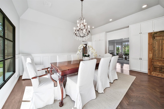 dining space with dark parquet flooring and a notable chandelier