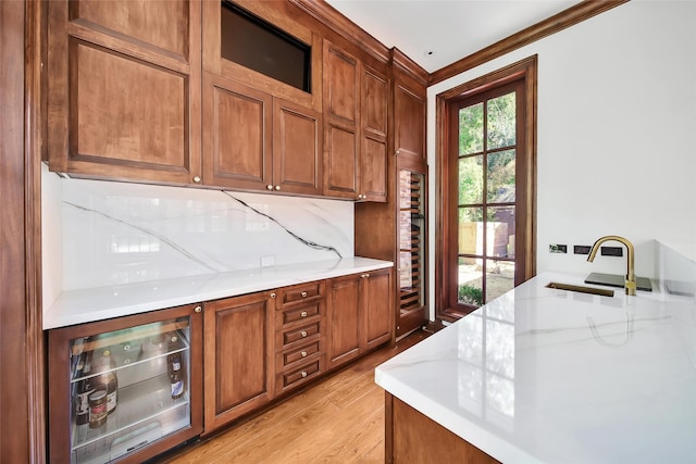 kitchen featuring decorative backsplash, light stone countertops, beverage cooler, and light hardwood / wood-style floors