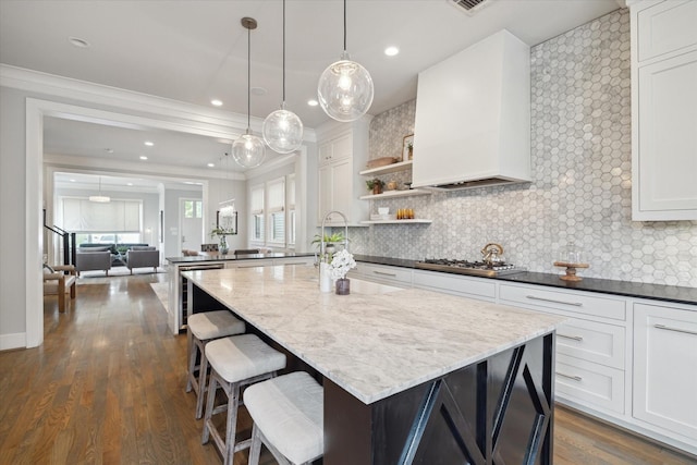 kitchen with white cabinets, stainless steel gas stovetop, plenty of natural light, and premium range hood