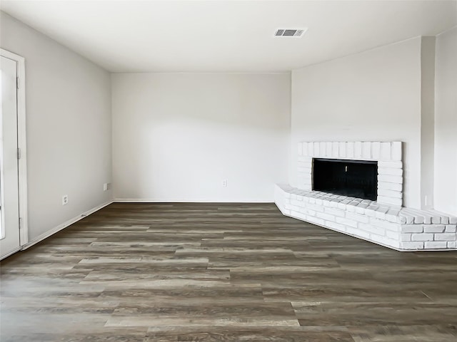 unfurnished living room with a brick fireplace and dark hardwood / wood-style flooring