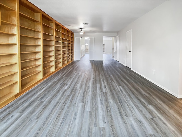 empty room with ceiling fan, dark hardwood / wood-style floors, and built in shelves