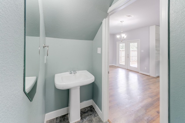 bathroom with lofted ceiling, french doors, sink, a notable chandelier, and hardwood / wood-style flooring