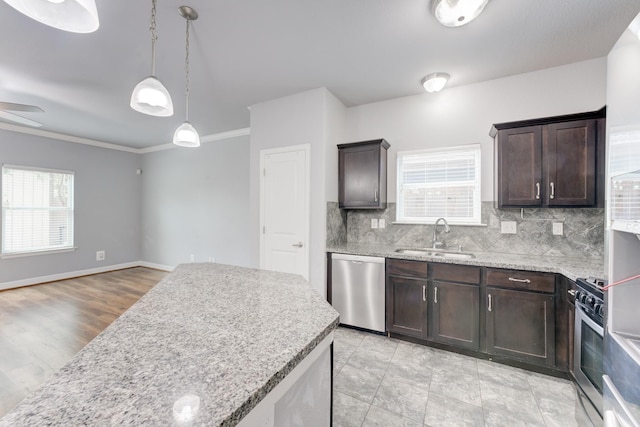 kitchen with appliances with stainless steel finishes, a healthy amount of sunlight, dark brown cabinets, pendant lighting, and sink