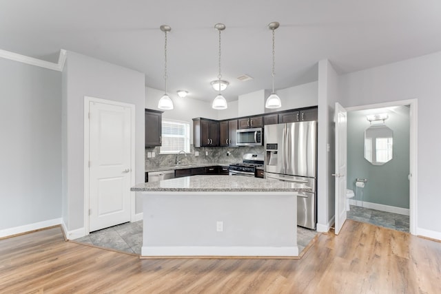 kitchen featuring stainless steel appliances, tasteful backsplash, a kitchen island, and sink