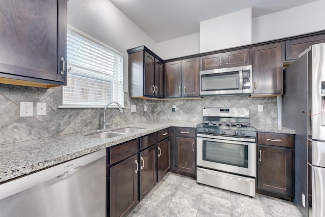 kitchen featuring light stone countertops, appliances with stainless steel finishes, dark brown cabinets, and sink