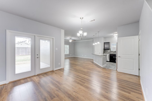 unfurnished living room with dark wood-type flooring, ceiling fan with notable chandelier, and french doors