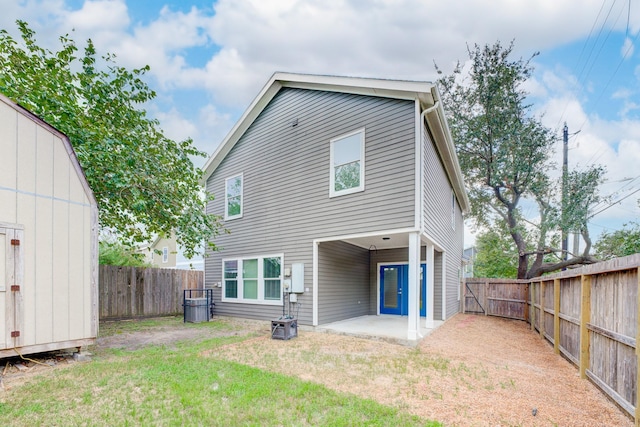 rear view of house with a yard, a storage shed, and a patio