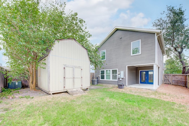 rear view of property featuring french doors, a storage unit, and a yard