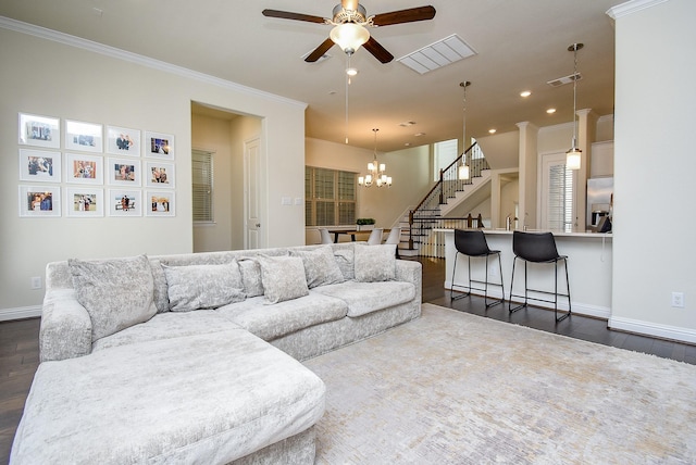 living room with ceiling fan with notable chandelier, dark wood-type flooring, and crown molding