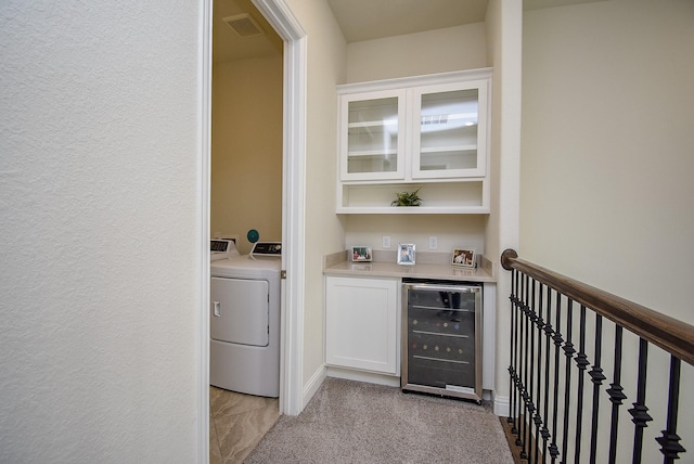 bar with light carpet, white cabinets, independent washer and dryer, and beverage cooler