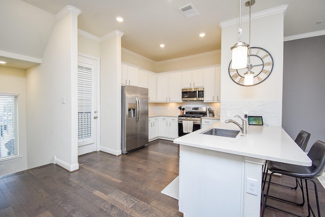 kitchen with kitchen peninsula, hanging light fixtures, a breakfast bar area, stainless steel appliances, and white cabinets