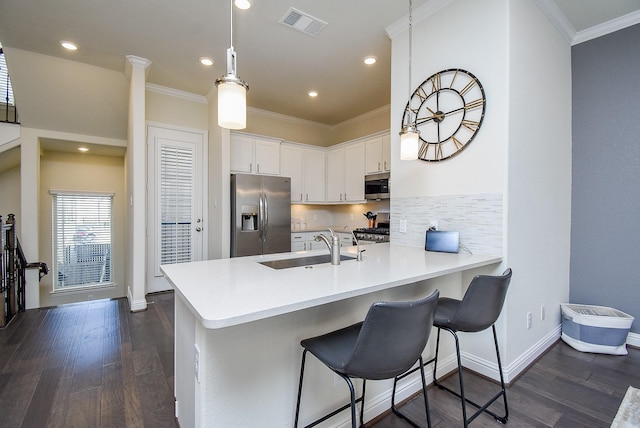 kitchen with pendant lighting, white cabinets, stainless steel appliances, sink, and kitchen peninsula