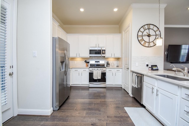 kitchen with pendant lighting, white cabinetry, appliances with stainless steel finishes, and crown molding