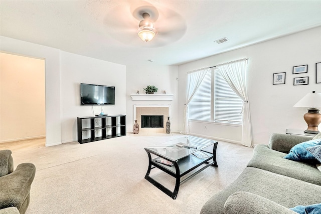 carpeted living room featuring ceiling fan and a tile fireplace