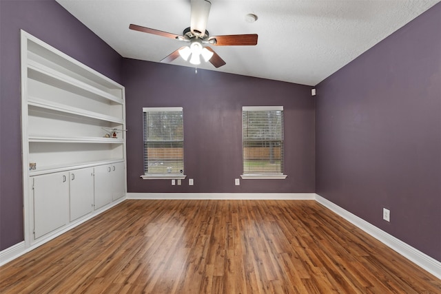 spare room with hardwood / wood-style flooring, ceiling fan, vaulted ceiling, and a textured ceiling