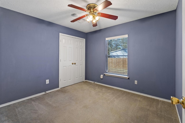 unfurnished bedroom with a textured ceiling, a closet, ceiling fan, and carpet